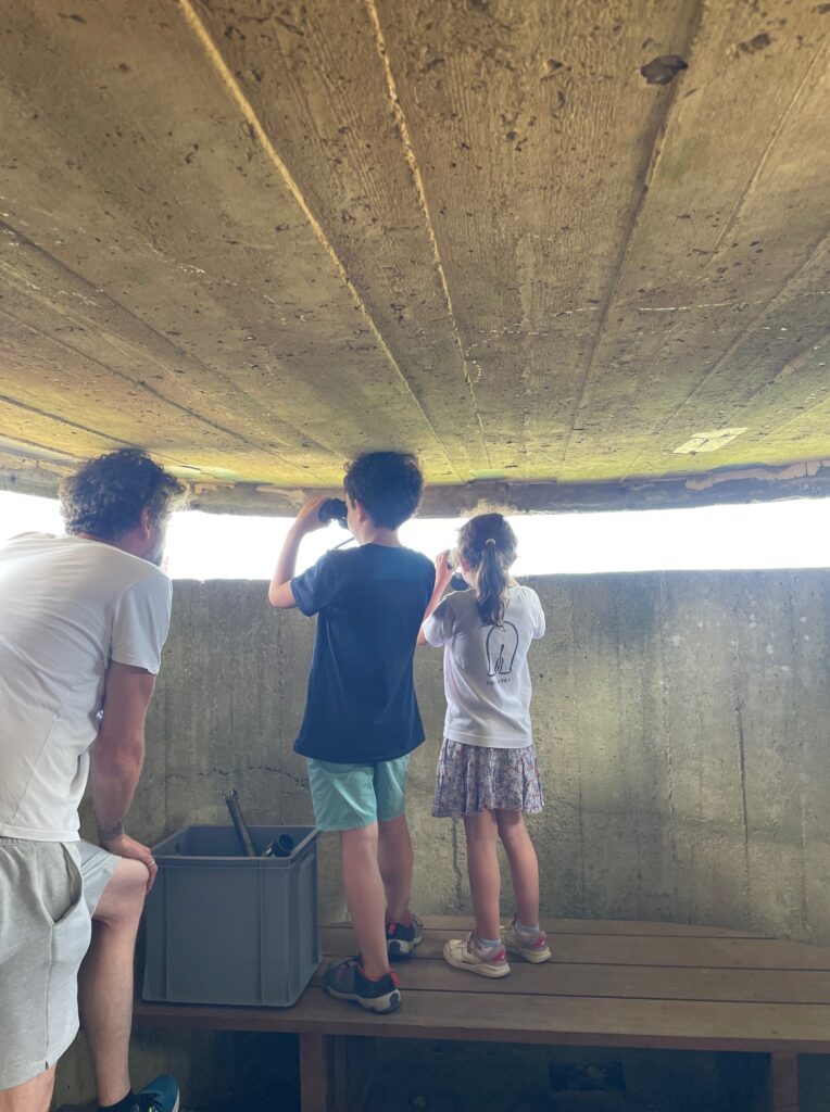 Deux enfants et le médiateur de dos, regardant dans des outils d'optique.