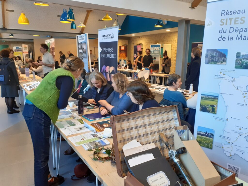 Forum culture avec stands d’informations sur le patrimoine Échanges entre visiteurs et exposants dans une salle moderne et lumineuse, dédiée à la promotion des sites historiques et activités culturelles, artistiques. 