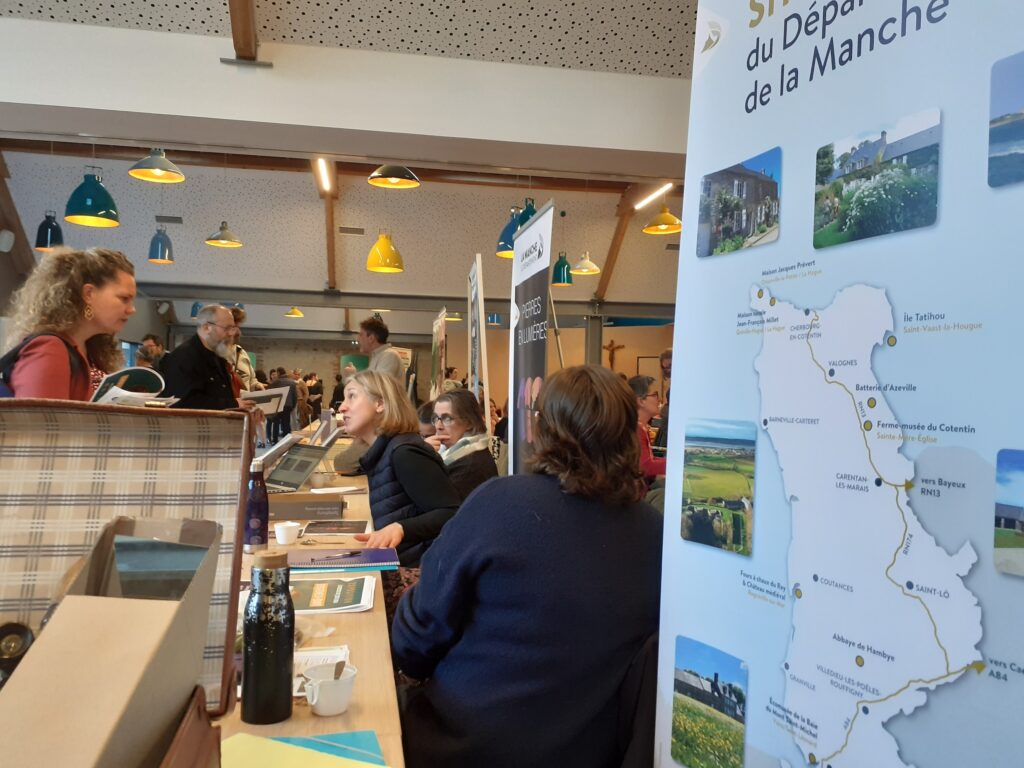 Stands d’information sur le patrimoine et la culture de la Manche lors d’un forum, avec brochures, cartes et panneaux présentant le réseaux des sites et musées du Département