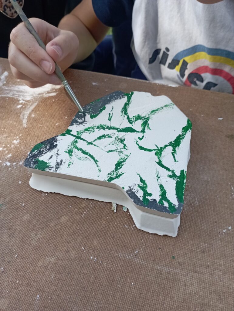 Enfant qui camoufle sa maquette en plâtre