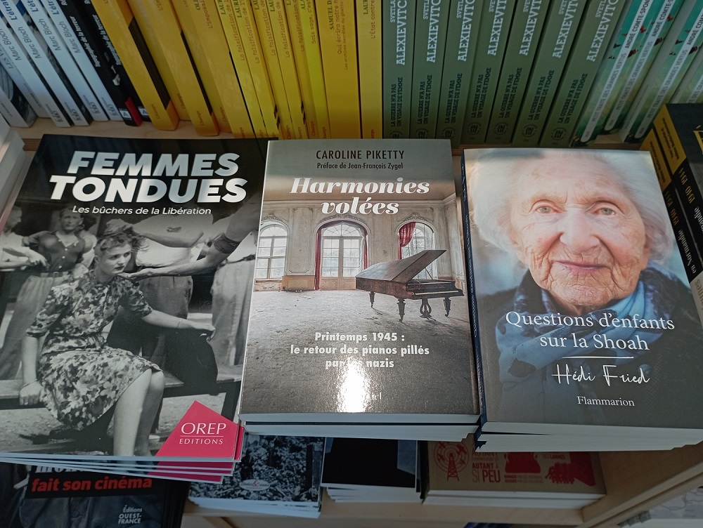 Trois livres, de gauche à droite "Femmes tondues, les bûchers de la Libération", "Harmonies volées (printemps 1945 : le retrour des pianos pillés par les nazis)" de Caroline Piketty et "Questions d'enfants sur la Shoah" de Heidi Fried. 