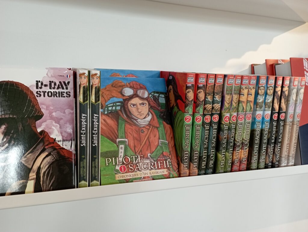 étagère avec plusieurs Manga : D-Day Stories, Saint-Exupéry, Pilote sacrifié