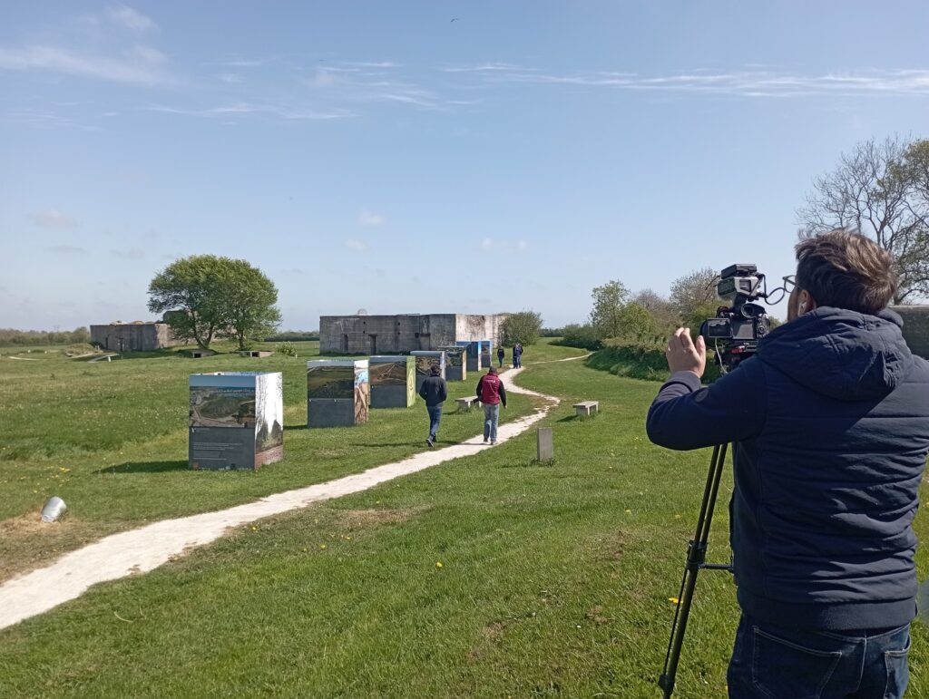 Reportage vidéo France 3, un vidéaste filme l'expo et deux personnes marchant de dos. 