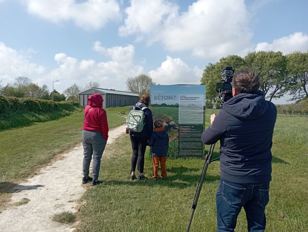 Journaliste filmant deux adultes et un enfant devant l’introduction de l’exposition Laisse Béton ?