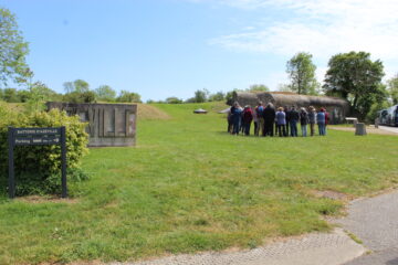 Groupe de visiteurs sur la partie en herbe devant une casemate pendant une visite guidée